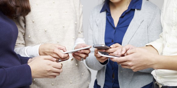 Group of young people using smartphones together