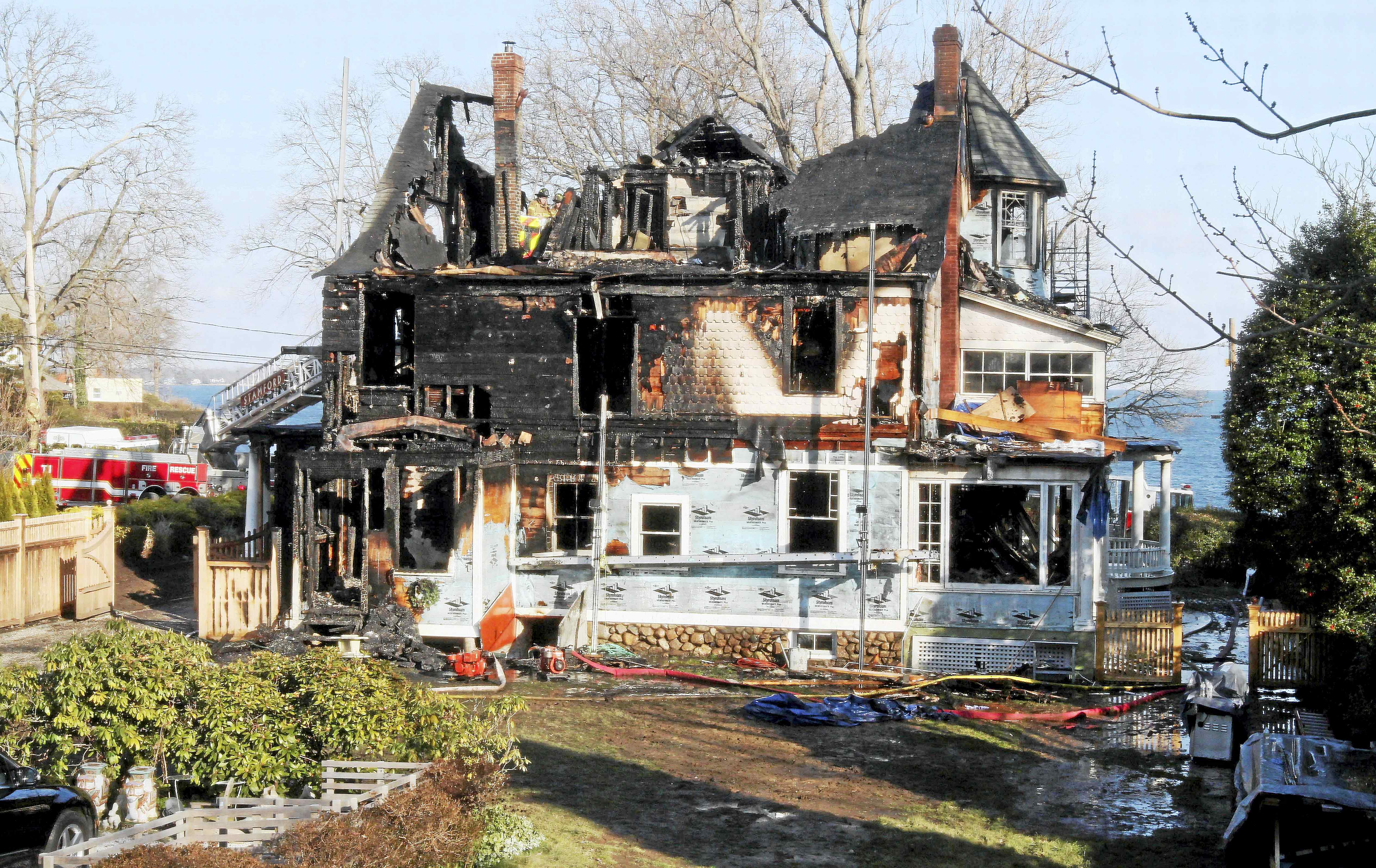In this Dec. 25, 2011 photo, firefighters investigate a house in Stamford, Conn. where an early morning fire left five people dead. The Hartford Courant reported Monday, May 9, 2016, that in a lawsuit deposition, contractor Michael Borcina said he lied to protect the children’s mother Madonna Badger, who was the one who left a bag of fireplace ashes in a mudroom, which were suspected of causing the fire.